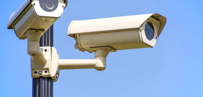 Caméras de surveillance extérieures montées sur un poteau sous un ciel bleu, assurant une surveillance vigilante
