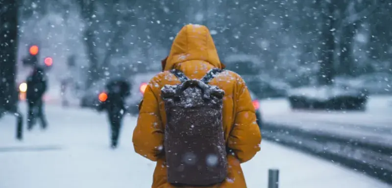 Personne portant un anorak et un sac à dos dans le froid hivernal