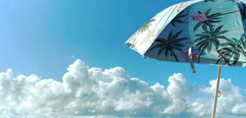 Parasols blancs et verts sur une plage ensoleillée, symbole des vacances d'été