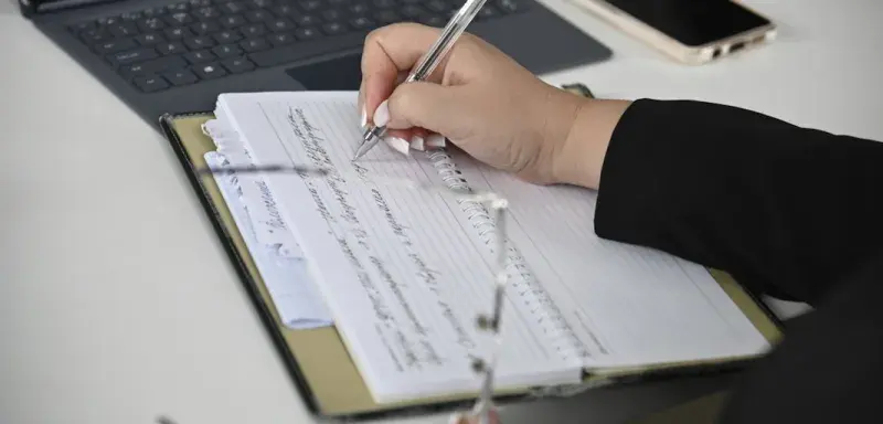 Une personne prenant des notes devant un ordinateur portable lors d'un audit financier