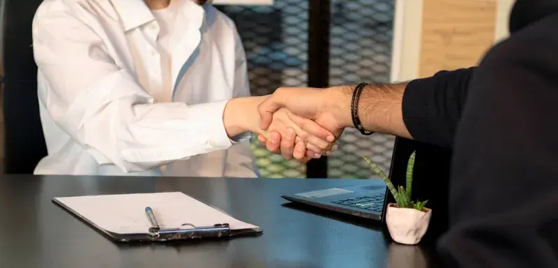 Un homme et une femme se serrent la main devant un ordinateur portable