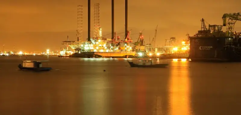 Raffinerie de pétrole illuminée de nuit, symbole des tensions sur les marchés énergétiques