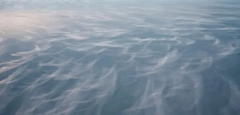 Paysage de montagne enneigé près d'un plan d'eau sous un ciel couvert