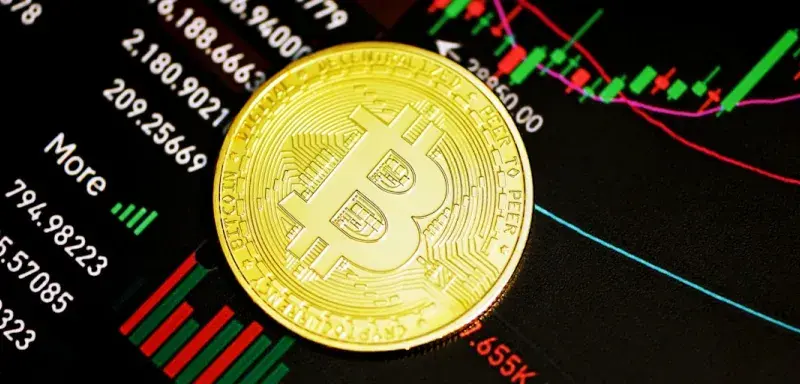 Pièce de Bitcoin dorée posée sur une surface sombre