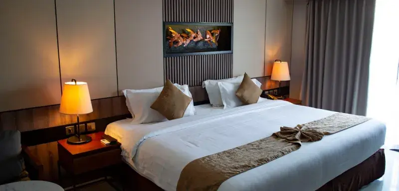 Chambre d'hôtel élégante avec linge de lit blanc et coussins décoratifs