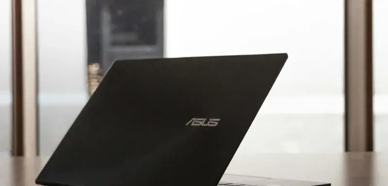 un ordinateur portable posé sur une table en bois