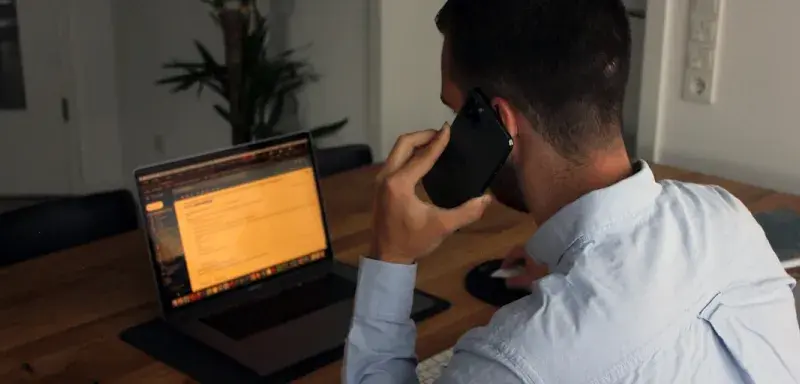 man in blue dress shirt holding black smartphone
