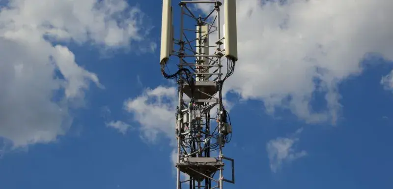 A tall cellular communication tower against a vivid blue sky, symbolizing modern technology.