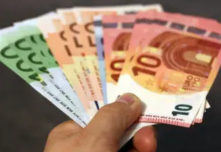 Éventail de billets en euros de différentes coupures tenus dans une main