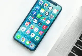 Smartphone posé sur un bureau à côté d'un ordinateur portable