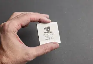 Gros plan sur une personne tenant une puce Nvidia sur fond gris