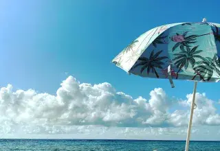 Parasols blancs et verts sur une plage ensoleillée, symbole des vacances d'été