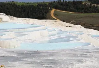 Terrasses naturelles de travertin avec eau bleue thermale au milieu des montagnes