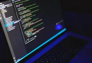 Un ordinateur portable affichant du code coloré dans un environnement sombre, illustration du développement technologique