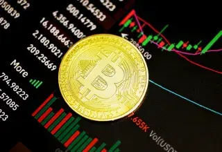 Pièce de Bitcoin dorée posée sur une surface sombre