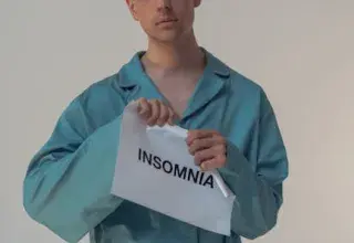 Jeune homme en pyjama tenant une pancarte Insomnia, illustrant les troubles du sommeil