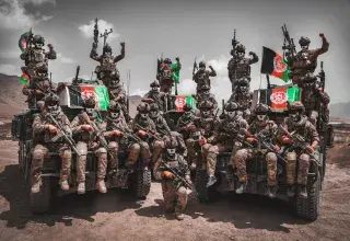 Des combattants afghans armés sur un véhicule militaire