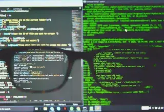 Lunettes posées sur un écran d'ordinateur affichant du code