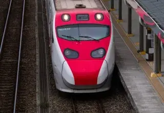Vue aérienne d'un train rouge et blanc à grande vitesse arrivant en gare