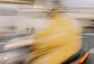 Abstract blurred image of a person riding a scooter in Kyoto, Japan.