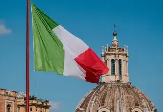 Captivating view of the Italian flag against Roman architecture and blue sky.