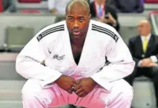 Two male adults engaged in judo practice on a dojo mat, showcasing martial arts technique.