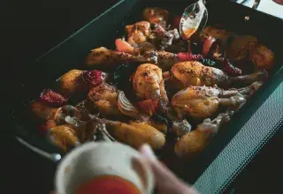 a person is spooning something into a pan of food