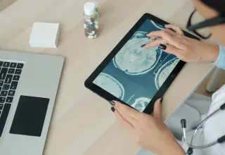 Doctor examining brain scan on tablet at desk.