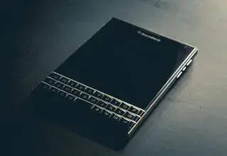 Close-up of a BlackBerry Passport smartphone with a physical keyboard on a dark surface.