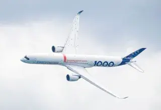 A stunning aerial view of an Airbus A350-1000 aircraft gliding against a cloudy sky.
